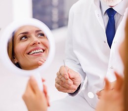 a patient checking her smile with a mirror