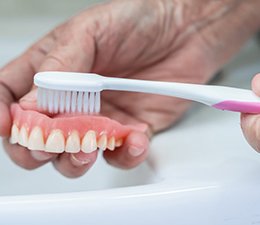 a person brushing and cleaning their dentures