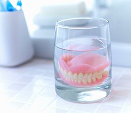 a pair of dentures in a glass cup of water