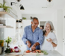 Man and woman laughing and cooking vegetables in the kitchen